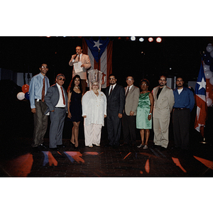 Nine people, including Carmen Pola, pose in front of a stage at a Festival Puertorriqueño event