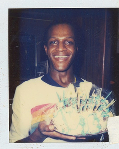 A Photograph of Marsha P. Johnson Smiling and Holding Up a Birthday Cake
