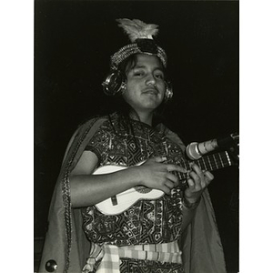 Young performer in traditional costume playing a ukulele-like instrument.