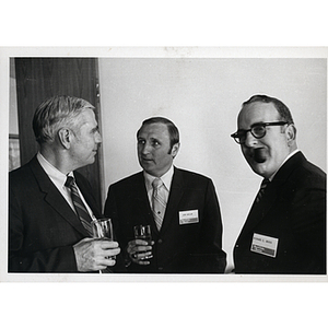John Whelam, at center, talks to an unidentified man while Richard C. Woods looks at the camera during a Boys' Club meeting