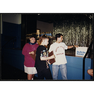 A man standing in front of the stage with a box while two girls with certificates look on during a Boys and Girls Club Education Awards ceremony
