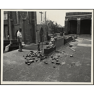 Several workers sit and stand around the memorial stone being removed during the Boys' Clubs of Boston Charlestown Clubhouse renovation at 15 Green Street