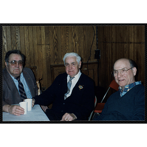 Three men sit at a table during a Bunker Hillbilly alumni reunion event