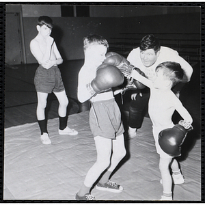 A boy punches his boxing opponent's face in the South Boston gymnasium