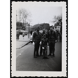 A boy stands with three men during a Patriots' Day parade
