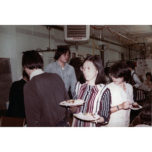 Woman holds plates of food from a buffet at Chinese Progressive Association's First Anniversary Celebration