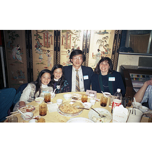 Man and woman pose for a picture with two young girls while seated at a restaurant table