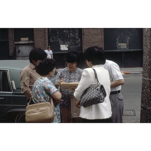 Suzanne Lee speaks with people around her on a sidewalk in Boston's Chinatown