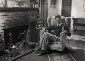 Carl Miller seated by fireplace