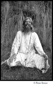 Bhagavan Das: full length portrait seated in a lotus position, laughing, facing the camera