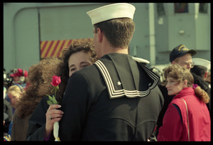 Woman with a rose hugging a sailor from the USS Roberts returning from Persian Gulf War duty