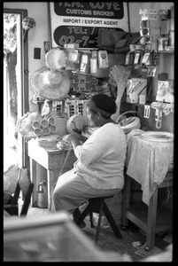 Woman plaiting palm leaf baskets in her store, Belize City