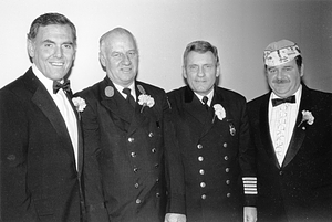 Mayor Raymond L. Flynn in tuxedo posing with Boston Deputy Fire Commissioner Leo D. Stapleton and two unidentified men