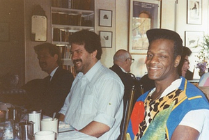 Photographs of Marsha P. Johnson Wearing a Colorful Patterned Sweater Vest, Sitting in a Restaurant with Friends