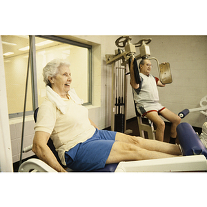 Man and woman use exercise machines in a gym