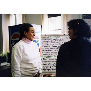 Two women standing in front of a flip chart.