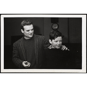 A man puts his arm around a boy while looking down to the left with him during a Boys and Girls Club event