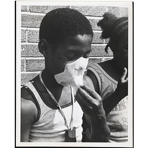 An African American boy removing a bubble gum bubble from his face