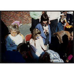 Girls receive face paint at a carnival