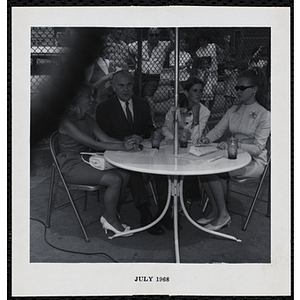 The panel of judges sitting under an umbrella during a Boys' Club Little Sister Contest