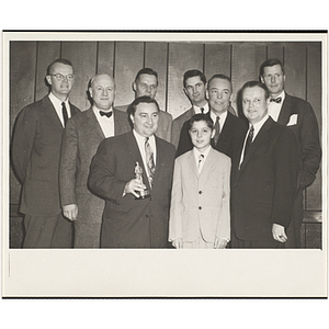 An award winner posing with several officers and guests, including State Senator John E. Powers, holding a trophy, at a Boys' Clubs of Boston awards event