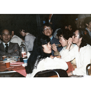 Men and women sit and eat dinner at a Chinese Progressive Association event