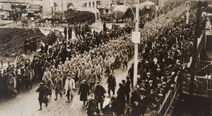 View from above of a military procession and civilians crowded along the street