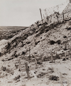 View of wooden crosses marking graves alongside a bunker and barbed wire