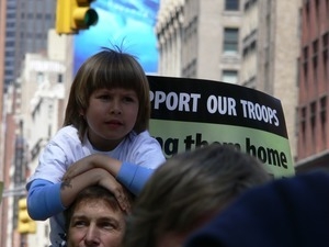 Child on her parent's shoulders, marching in the streets to oppose the war in Iraq