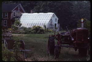 Tractor parked in front of greenhouse and house, Montague Farm Commune