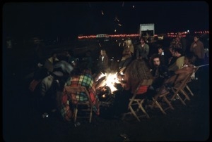 Gathering around a campfire at night during the Woodstock Festival