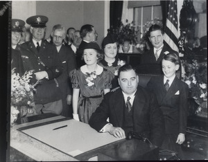 Charles F. Hurley at the dedication of Cyrus Edwin Dalin's statue of Paul Revere: Hurley seated at a desk with family, police and others in the background