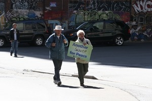 Older protesters joining the march opposing the war in Iraq, carrying a sign reading 'Another senior for peace'