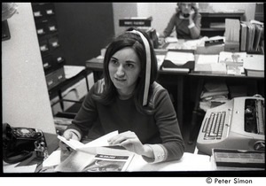 Young woman (secretary?) seated at a desk in the Boston University Placement Office, at start of student occupation to protest on-campus recruiting by Dow Chemical Co., manufacturer of napalm
