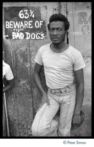 Jimmy Cliff standing by a sign 'Beware of tigers and bad dogs' near his old home on Spanish Town Road