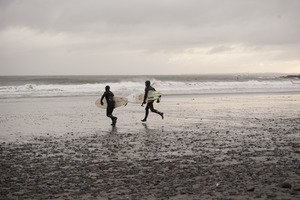 Two surfers running with their boards toward the water