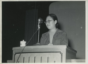 Unidentified woman speaking at a microphone