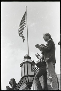 Demonstration at State House against the killings at Kent State: protesters applauding, American flag in background