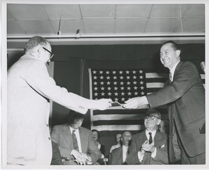 Unidentified man presenting gift to client on stage at Institute Day