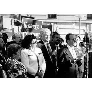 Man at a microphone standing next to Senator Kennedy during a campaign stop.