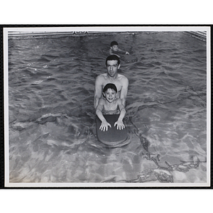 A man poses with a boy in a pool