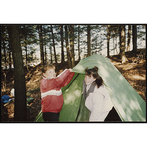 Two girls pitch a tent outdoors