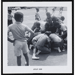 A group of closely huddled boys play a game on a playground during Tom Sawyer Day