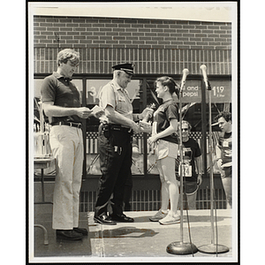 A police officer hands a runner a trophy on a dais during the Battle of Bunker Hill Road Race