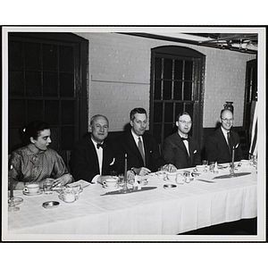 Four men sit at a table looking at the camera, while a woman looks off to her left, during the Important People Awards