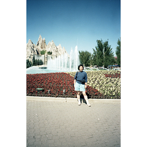 Lydia Lowe stands in front of a flowerbed and a rock structure in a botanical garden