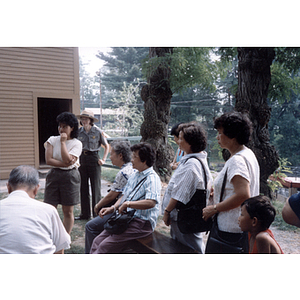 Association members sit outdoors, listening to a speaker