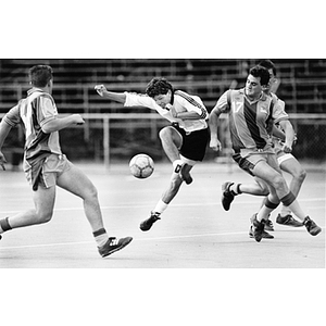 Tom Rumaner, center, dodging two players in a soccer match against Suffolk University