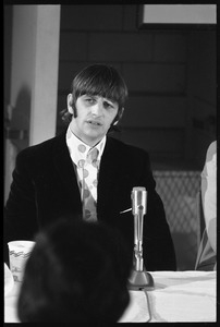 Ringo Starr seated in front of a microphone at a table, during a Beatles press conference