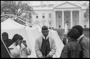 Strikers and supporters milling about outside a tent, the White House in the background